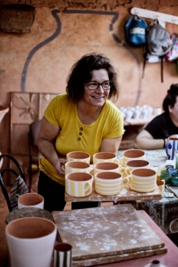 woman moving hand painted coffee cups in a pottery studio in Corval in portugal