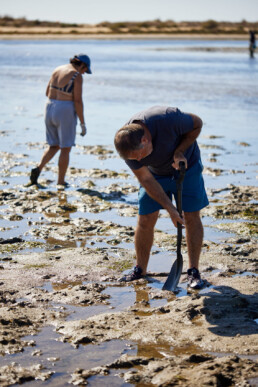 man digging for sand worms at the beach in the portugese algarve