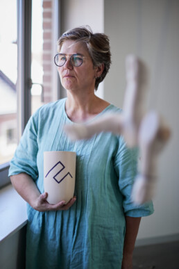 ceramic artist gazing in the distance holding a ceramic vaze