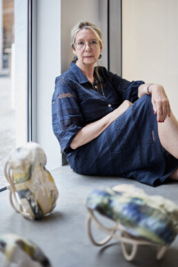 ceramic artist sitting on the floor with her ceramic artwork in the front