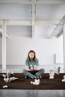 ceramist sitting on the floor amidst his ceramic art work